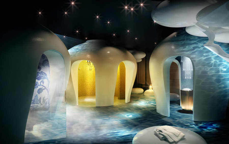 Cave-like spa interior with reflective blue water and gold mosaic archways
